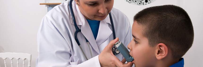 female doctor with young boy using an asthma inhaler