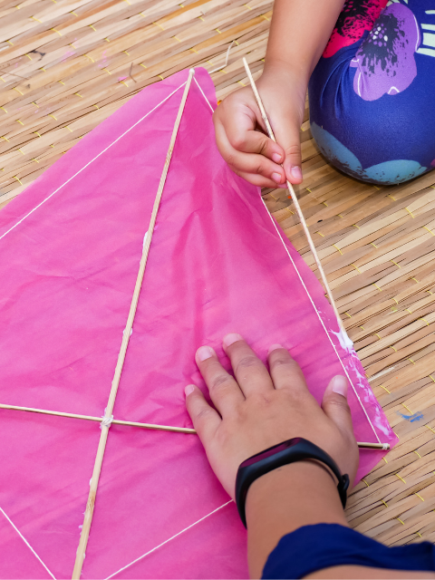 Children's hands creating a paper kite