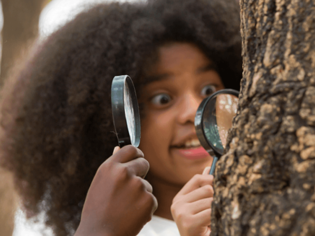 Girl looking at tree with magnifying glass