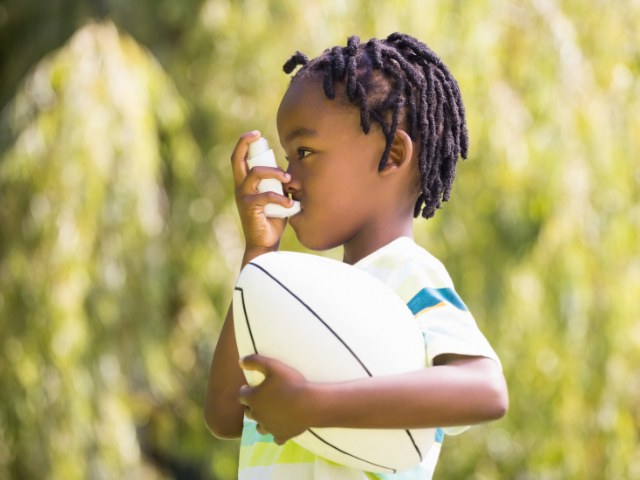 Young child holding a ball and using an inhaler
