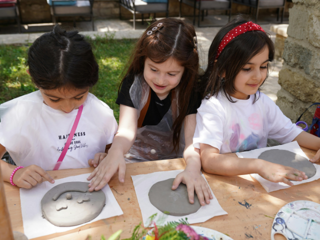 Three young girls at a table outdoors doing an educational activity