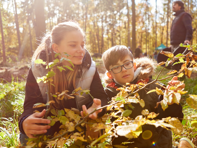 Two young people looking at a plant outdoors