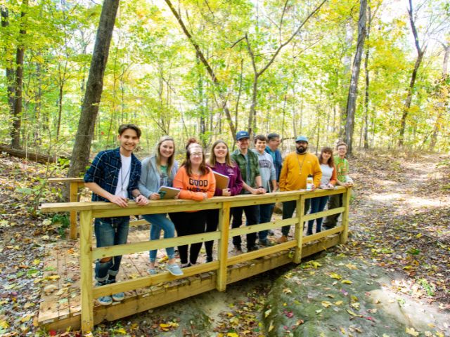 students from University of Southern Indiana stand on a new trail bridge
