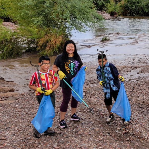 Mom and sons at a beach clean up with garbage bags
