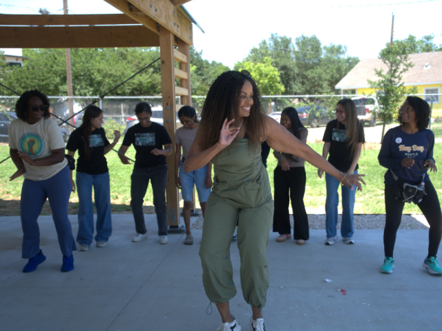 Woman dancing with others outdoors near pavillion