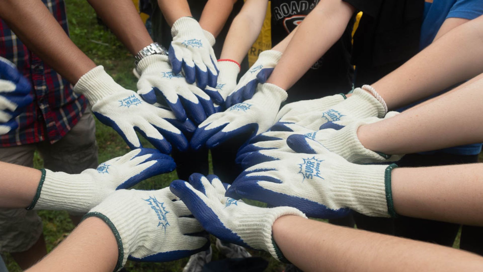 a group of volunteers put their hands together in a circle before an activity 