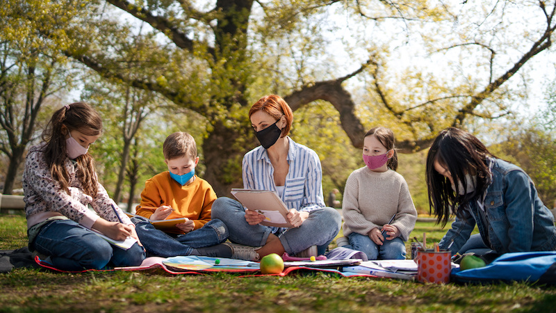 students sitting with teachers in the outdoors learning