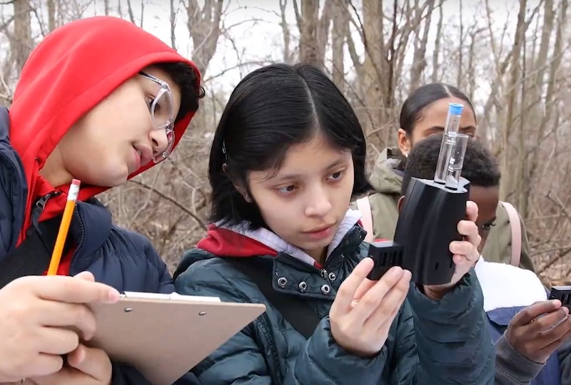 Students using scientific equipment outdoors