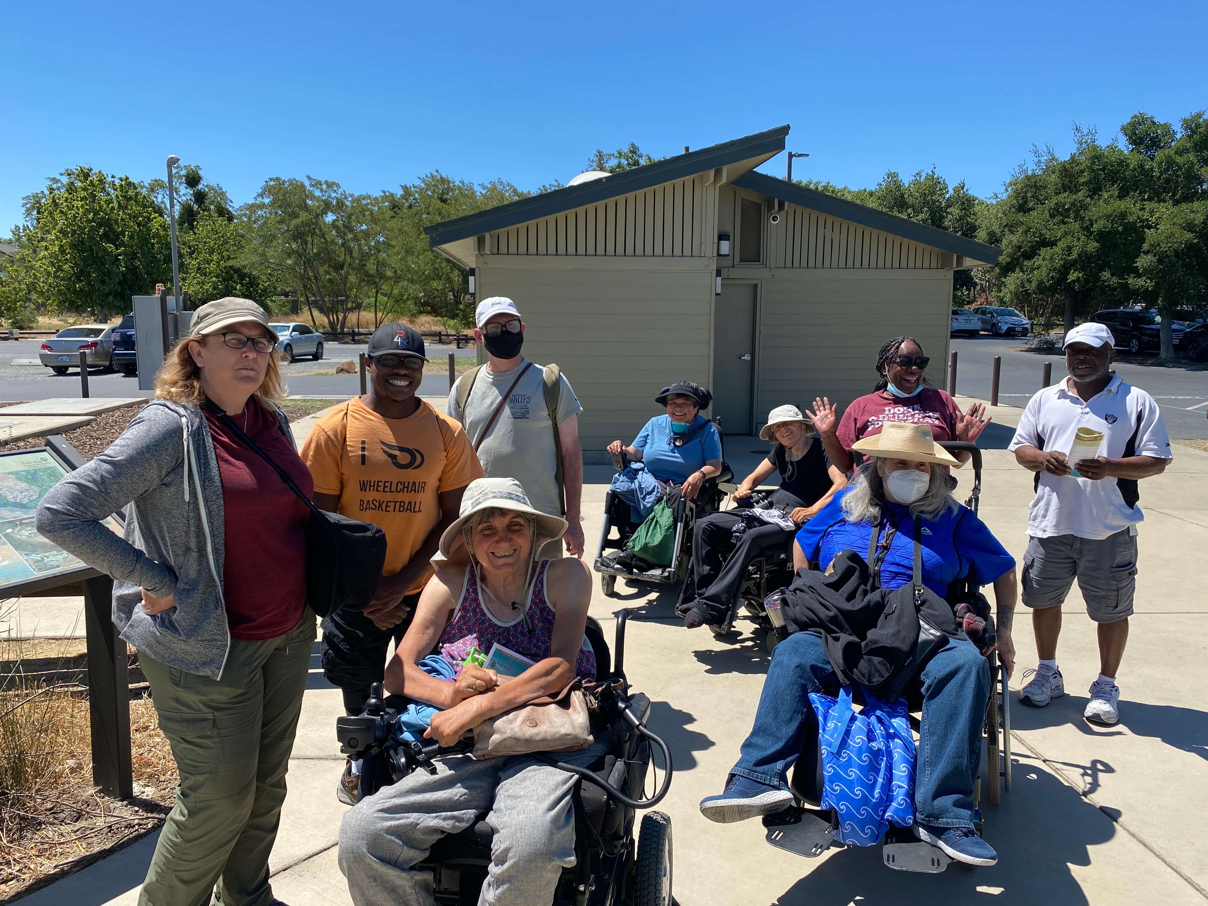 A racially diverse group of people with various physical disabilities including some in wheelchairs, arrive at Big Break Regional Shoreline for All Abilities Day 