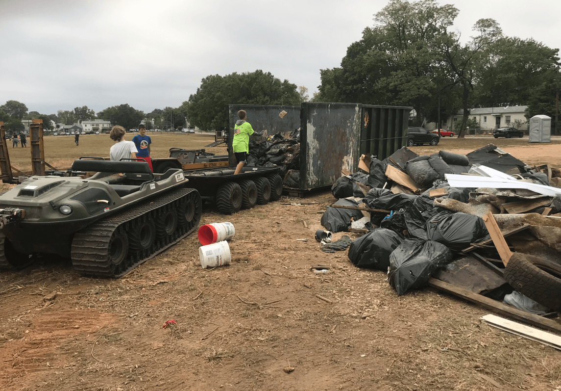 Volunteers wait by dumpsters for trash collected.