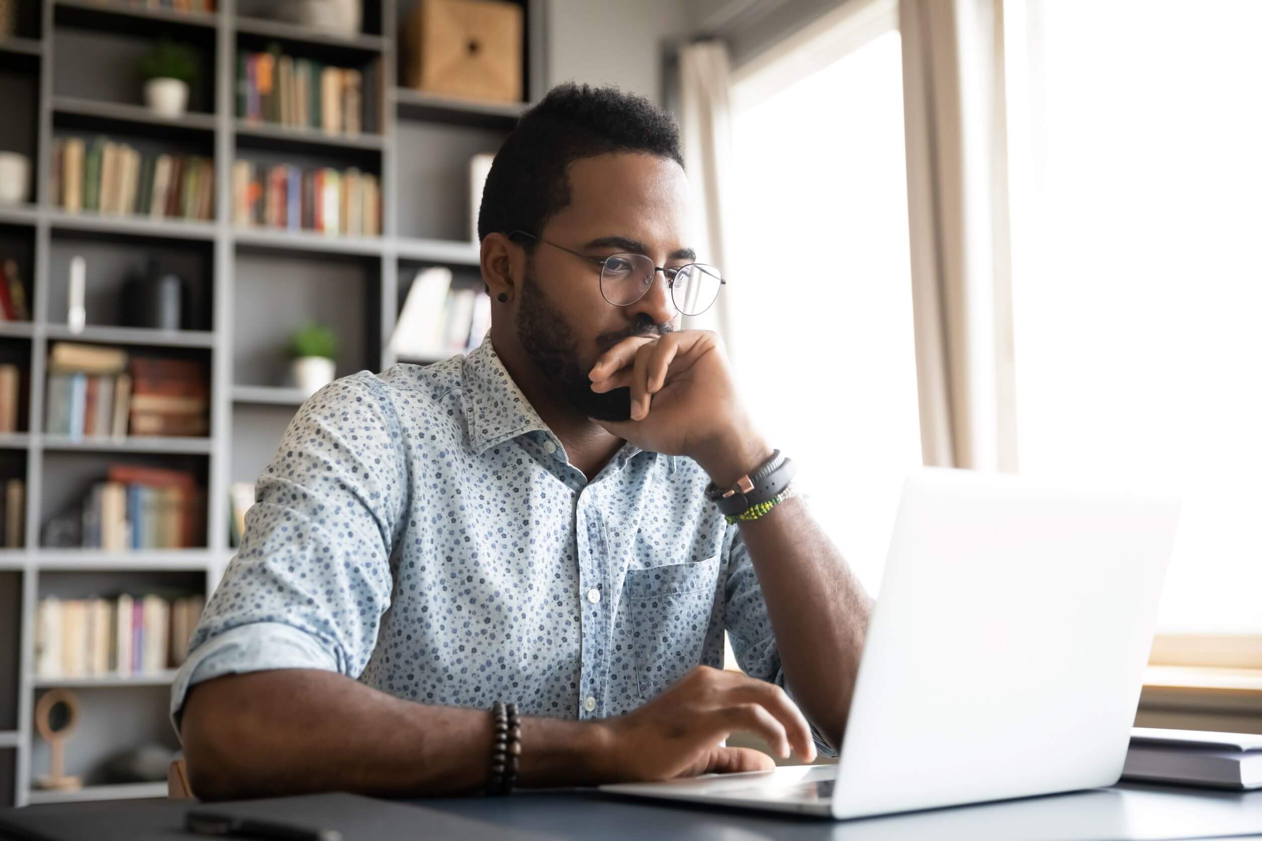 Consumer man sitting at computer with thoughtful look as he researches companies sustainability commitment