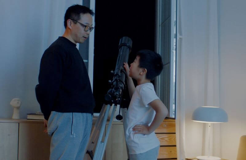 Father and son looking at star from telescope at home.