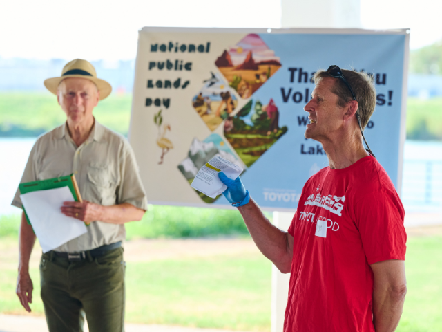 Man with red shirt standing in front of a banner