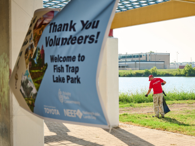 Banner in the wind with volunteer in the background picking up trash