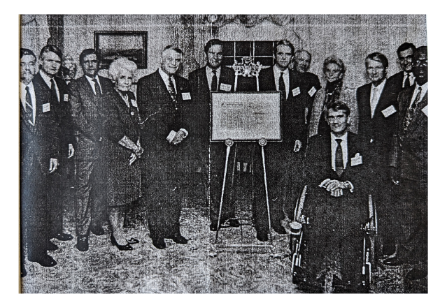Senate Representatives standing near a signed document on an easel.