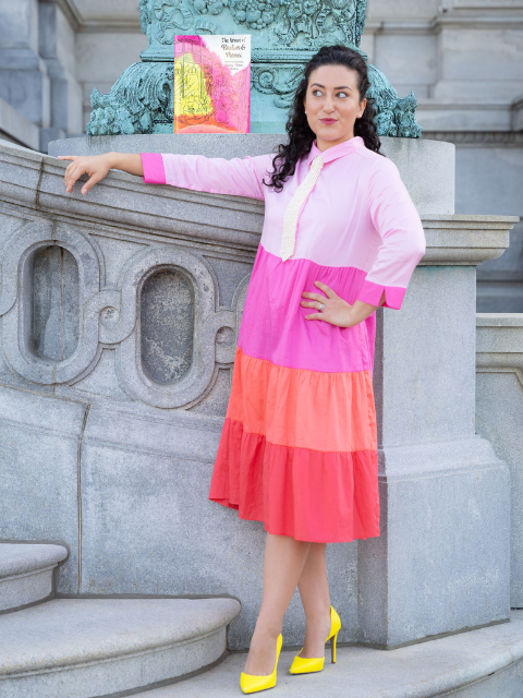 Lindsay Cordeiro standing in colorful dress near a book she illustrated