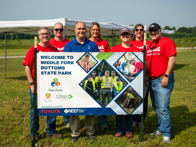 Group wearing red shirts holding a banner