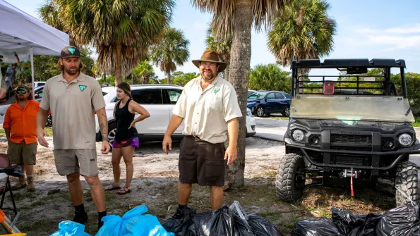 Bureau of Land Management site manager stands with collected trash in bags during national public lands day event