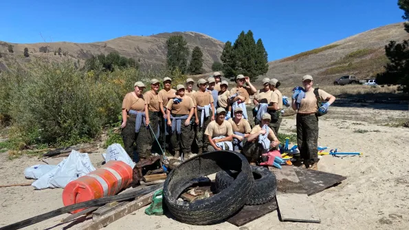 a group of volunteers stands around a pile of collected trash on National Public Lands Day
