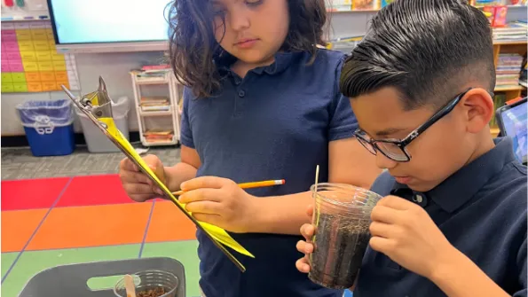 Two middle school kids looking closely at a science experiment