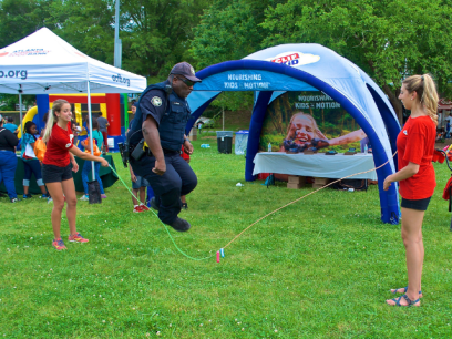 Police officer jumping rope being held by two volunteers