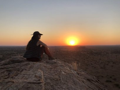 Woman sitting on a rock watching the sunset