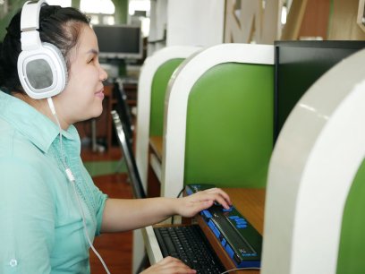 A woman with visual impairments uses a special keyboard while on the computer
