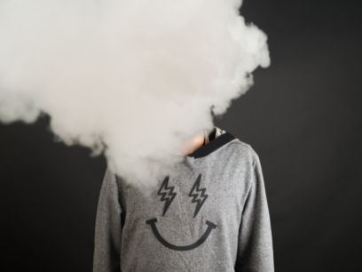 A person's face is covered by a cloud of smoke