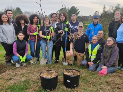 students from McCaskey high school stand near two trees ready for planting