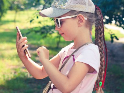 a young girl uses a cellphone outside