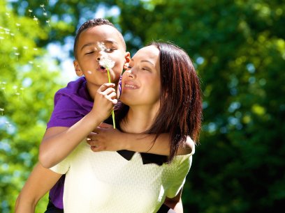 Boy blowing a dandelion with his mom