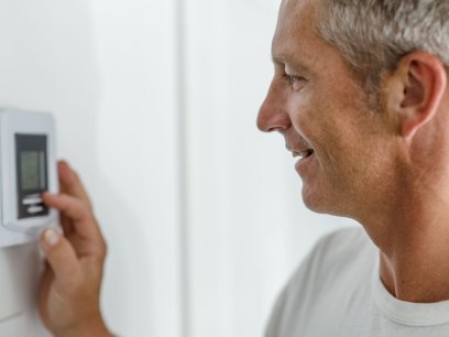 Smiling daddy adjusting the thermostat