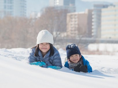 Brother and sister playing in the snow outside