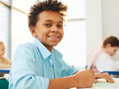 Smiling middle school student at a desk in class