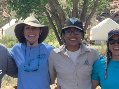 Photo of Bureau of Land Management and nonprofit partners arm in arm smiling.