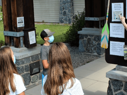 Forest Service staff pointing to announcement board instructing group of middle school students. 