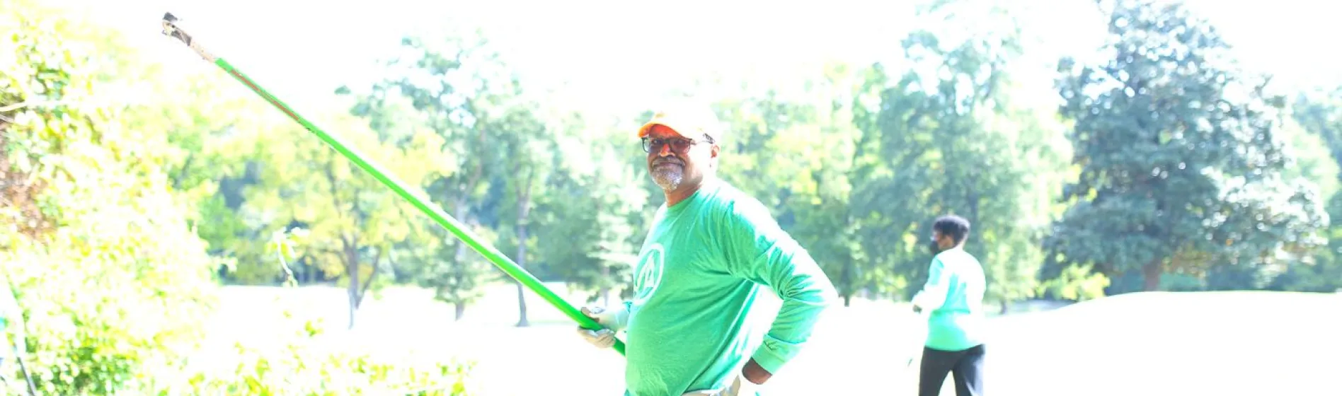 an international paper employee stands with a tree trimmer during an outdoor volunteer event
