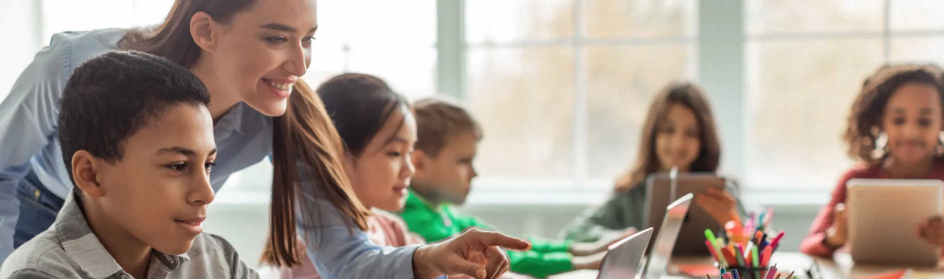 Teacher pointing to something on a computer to a student