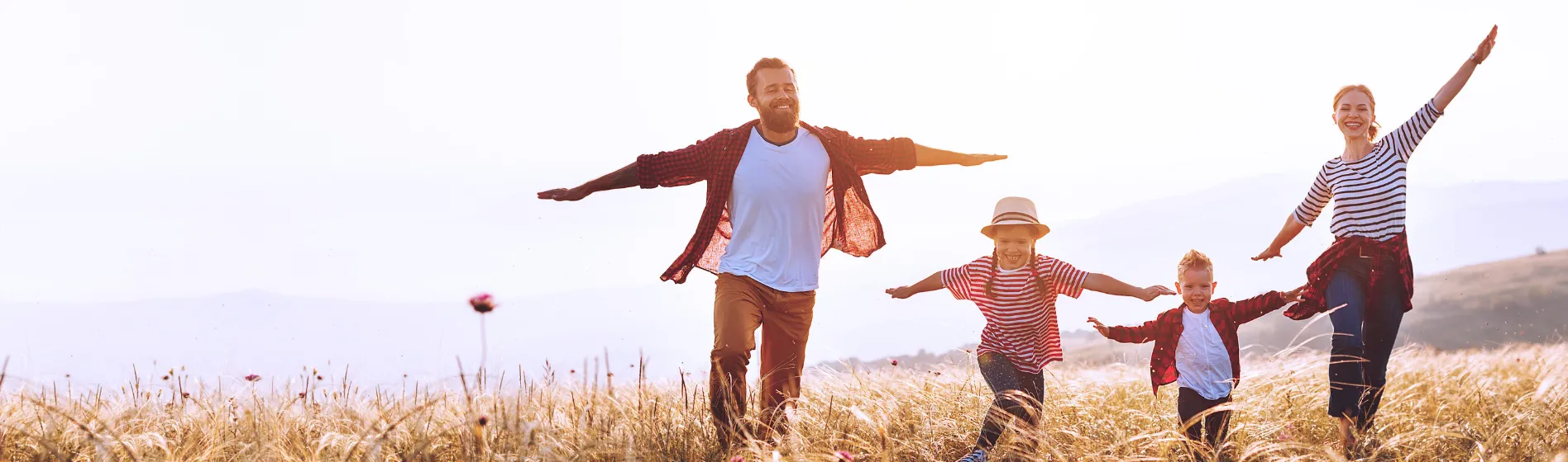 Family holding hands and running through field on a sunny day