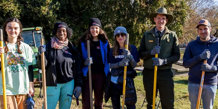 A group of volunteers stands with shovels at Kenilworth National Park