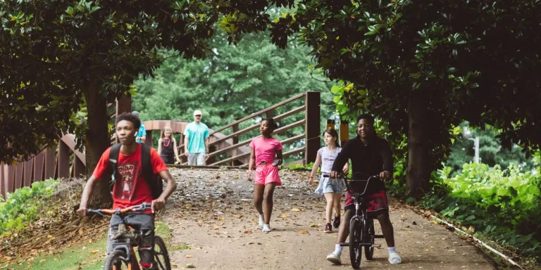 a group of people walk and bike across a bridge at the Park Along the River in New Albany MS