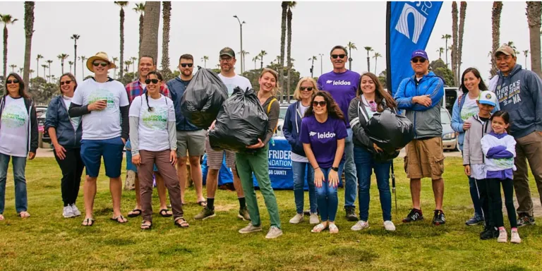 Volunteers standing in a row with a garbage bag