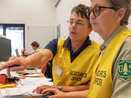 two female forest service employees work together on a computer