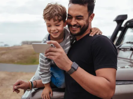 Man with young boy smiling and looking at phone