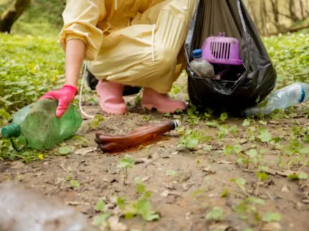 a person collects trash that is on the trail in the forest