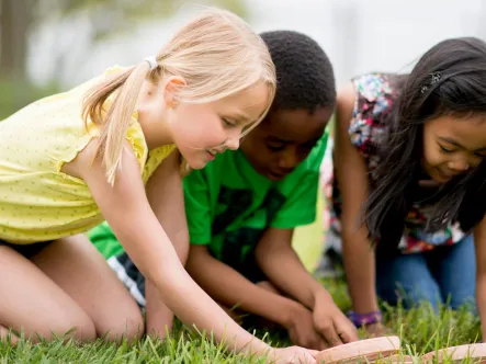 students using magnifying glasses to inspect the grass