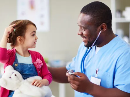 a doctor smiles at a young girl during an environmental health screening