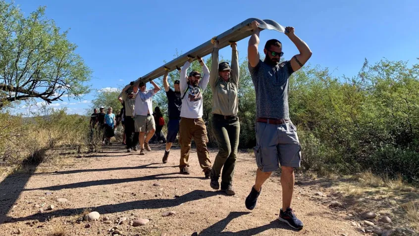 volunteers carry a large guardrail over their heads during a National Public Lands Day event