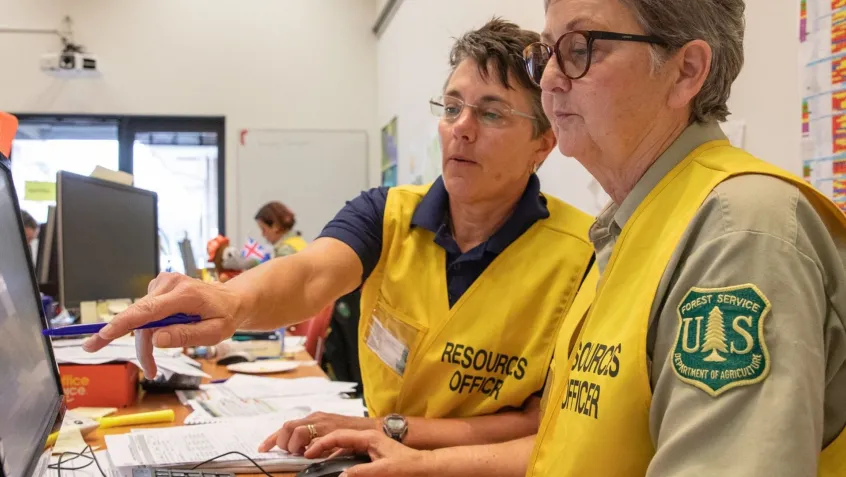 two female forest service employees work together on a computer