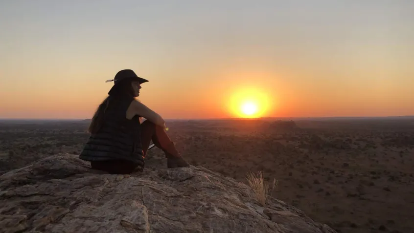 Woman sitting on a rock watching the sunset